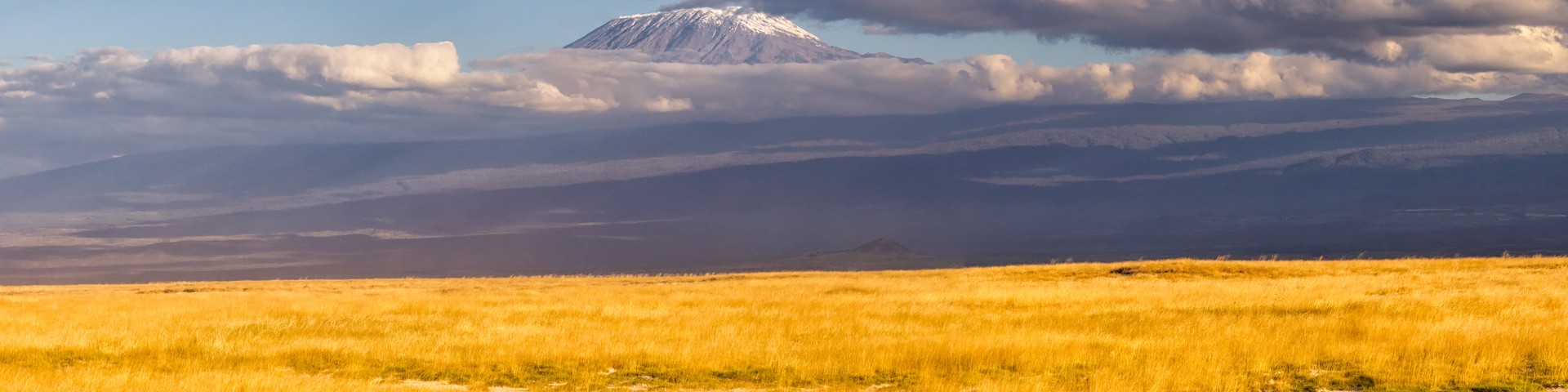 Kilimanjaro's snow-capped summit at night above a glowing camp